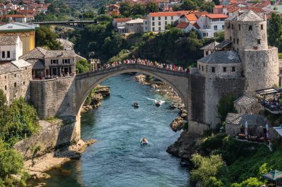 This photo captures a river running through Mostar city, with a prominent Old Bridge in the background, Bosnia and Herzegovina