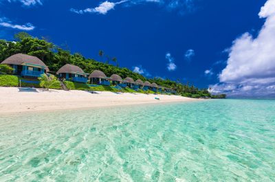 Tropical beach with with coconut palm trees and villas, Polynesia